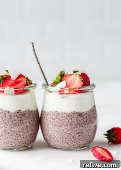 Two jars of strawberry chia seed pudding topped with fresh strawberries