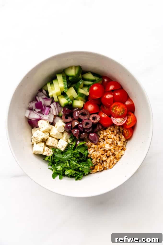 Mediterranean Farro and Feta Salad 4 A large salad bowl filled with colorful, freshly chopped vegetables, cooked farro, and crumbled feta cheese, ready for dressing.