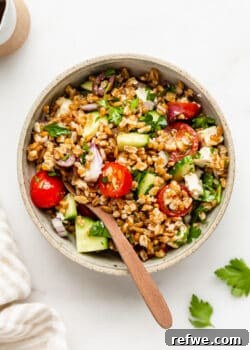 a bowl of Greek Farro Salad with a wood spoon in it