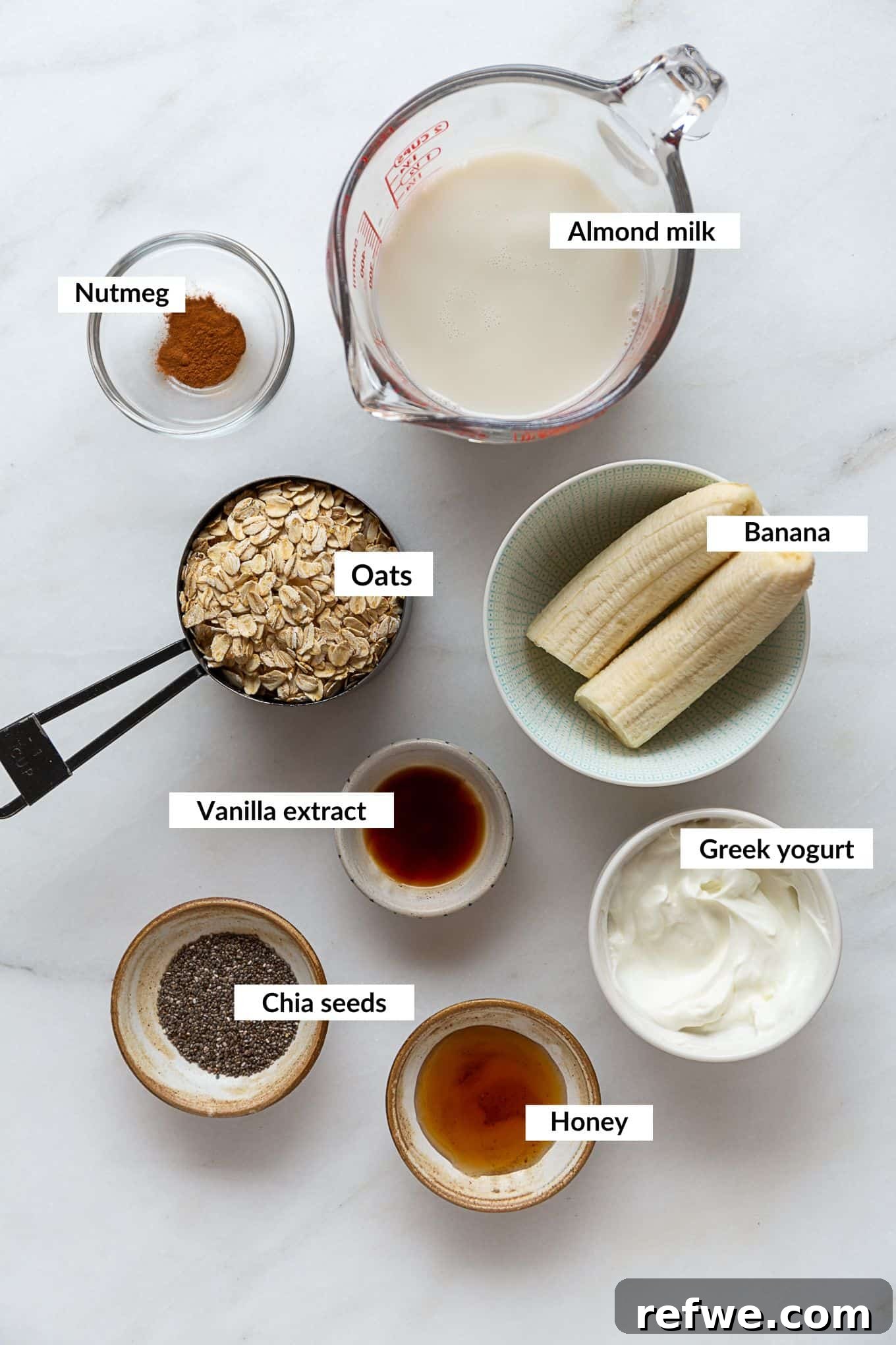 Creamy Banana Overnight Oats 3 A flat lay photograph showcasing all the key ingredients needed to prepare a batch of healthy banana overnight oats, including rolled oats, chia seeds, a perfectly ripe banana, and creamy yogurt, artfully arranged on a light surface.