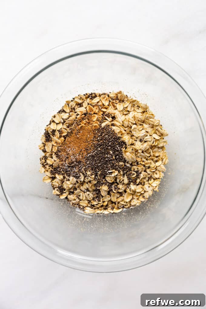 Creamy Banana Overnight Oats 4 A mixing bowl containing dry ingredients: rolled oats, chia seeds, and ground nutmeg, perfectly arranged and ready for the next step of combining with wet ingredients.