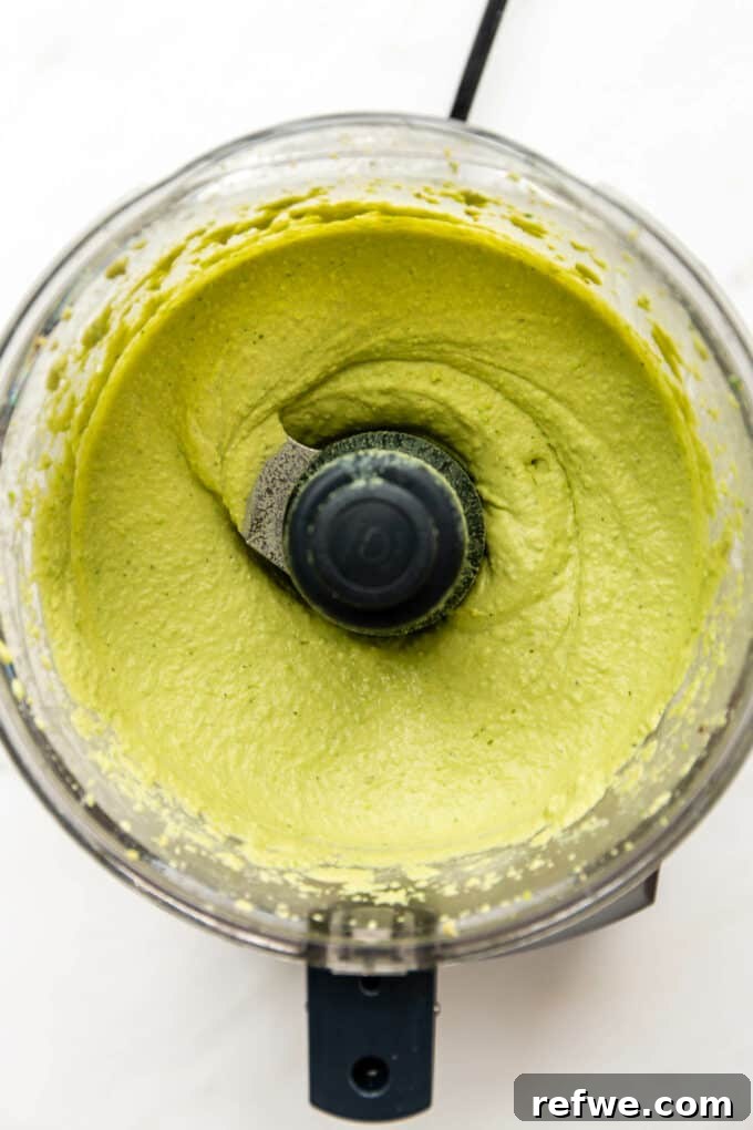 Green pea hummus being blended in a food processor, showing its smooth and creamy consistency.
