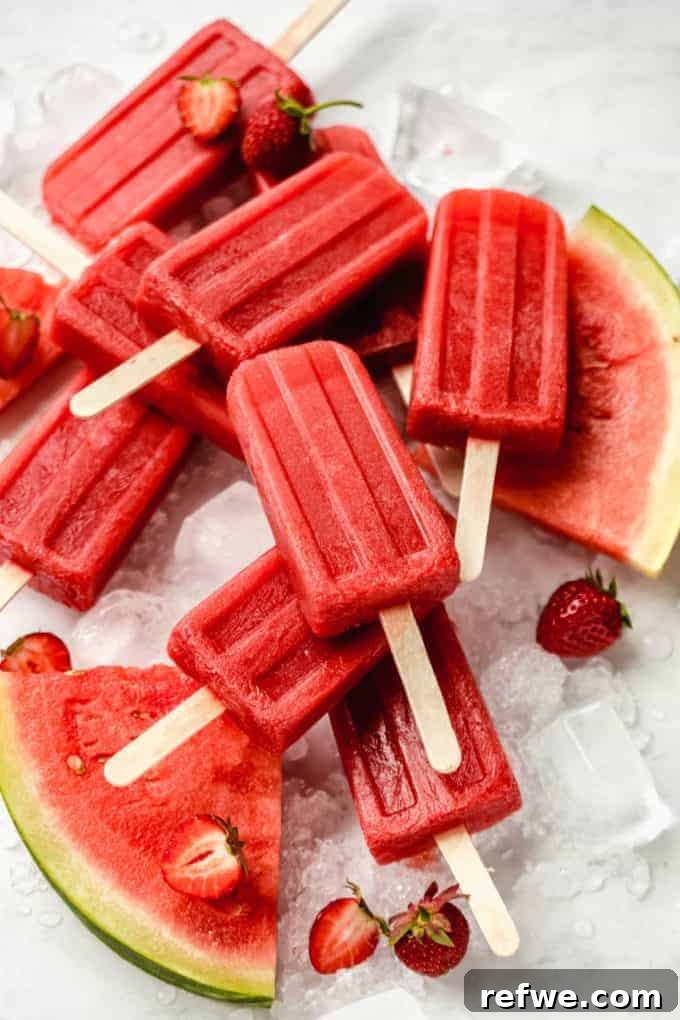 Beat the Heat: 8 Refreshing Homemade Popsicle Ideas 3 Three bright pink Strawberry Watermelon Popsicles arranged upright, showcasing their refreshing and fruity layers, set against a clean background.