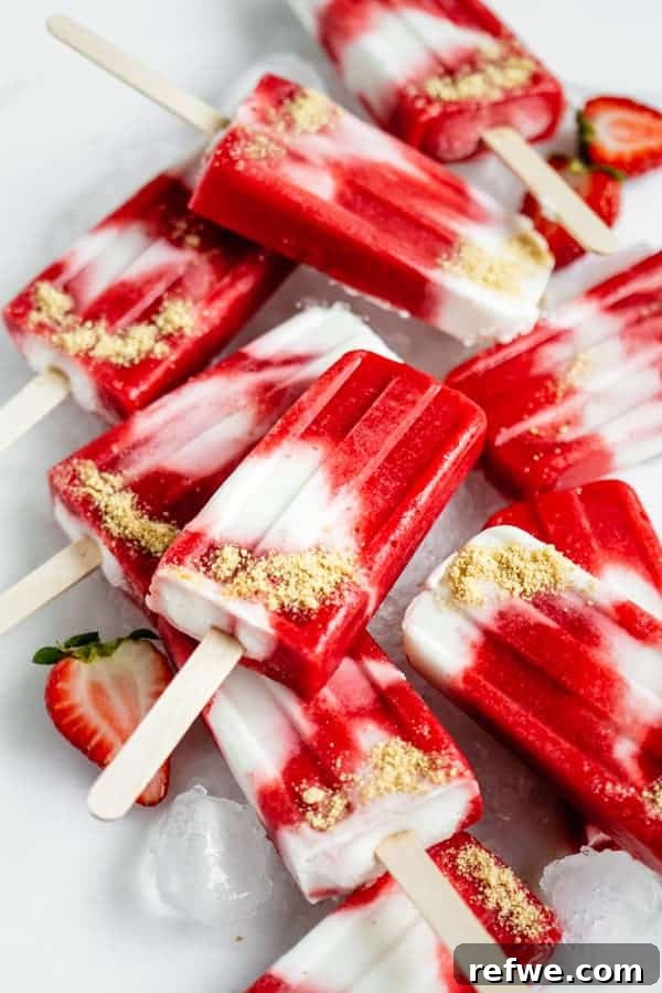 Beat the Heat: 8 Refreshing Homemade Popsicle Ideas 7 Three delicate pink Vegan Strawberry Cheesecake Popsicles, each with visible strawberry flecks and a creamy base, arranged aesthetically.
