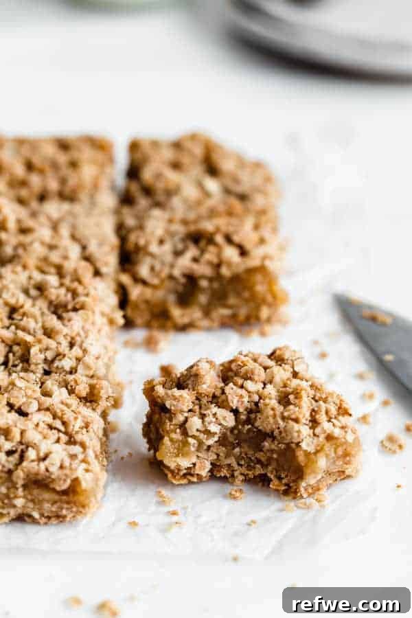 Savor the Season: 14 Fall Apple Recipes 15 Healthy Apple Pie Bars topped with a delicious streusel crumb, neatly sliced into squares on parchment paper.