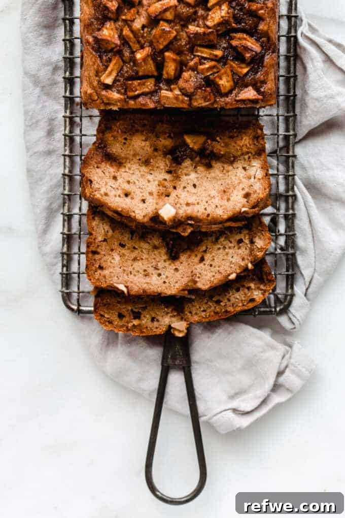Savor the Season: 14 Fall Apple Recipes 7 A freshly baked, golden-brown loaf of Cinnamon Apple Bread, sliced to reveal apple chunks and cinnamon swirls, presented on a rustic cutting board.