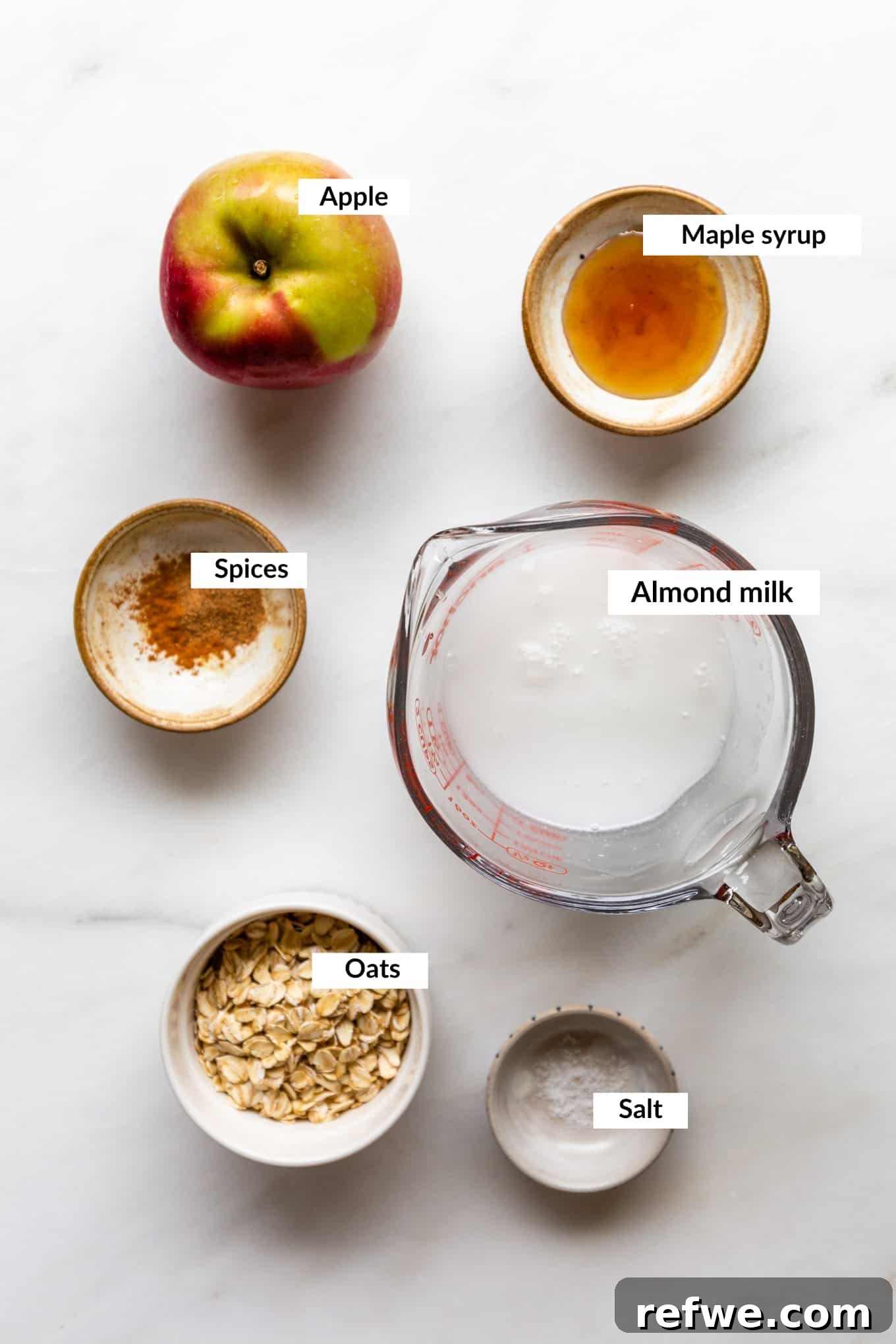 Warm Apple Pie Oats 3 A flat lay image displaying all the key ingredients for apple pie oatmeal, including oats, apples, cinnamon, and maple syrup.