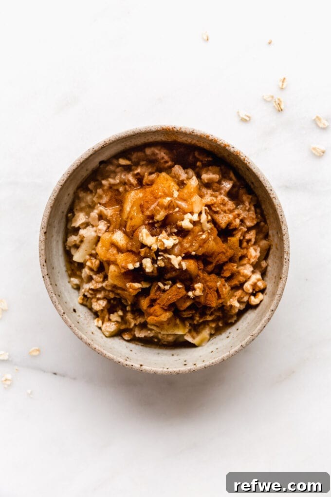 Warm Apple Pie Oats 9 A beautifully plated bowl of apple pie oatmeal, generously topped with cooked cinnamon apples and crunchy walnuts.