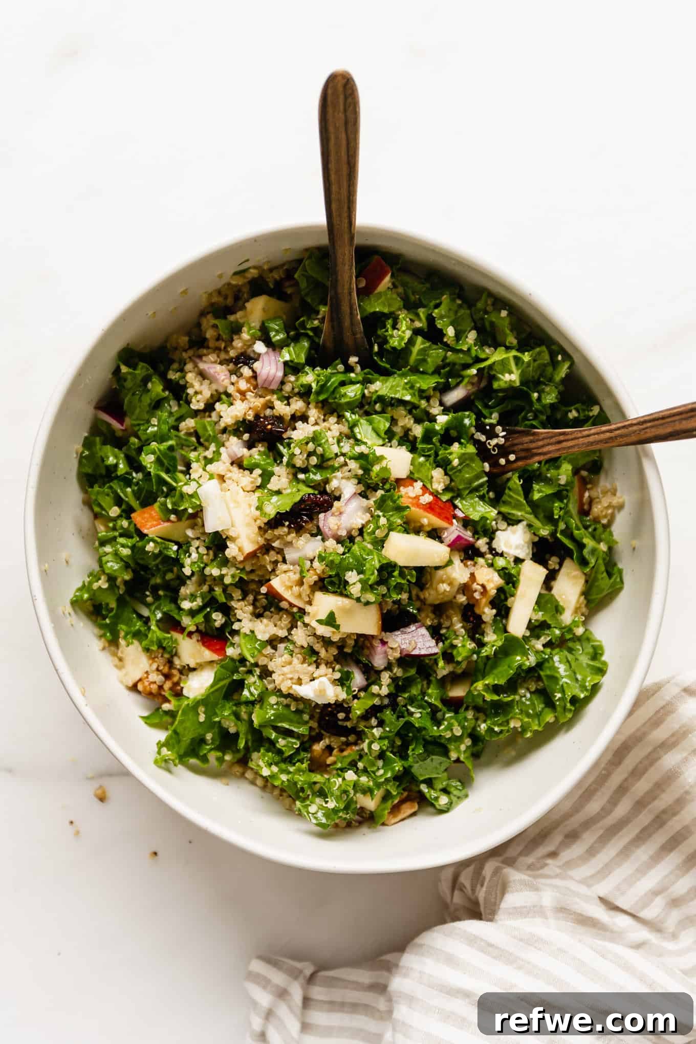 Vibrant Apple Cranberry Quinoa Salad 6 A beautifully presented apple quinoa salad in a large bowl, accompanied by two wooden serving spoons, ready to be enjoyed.
