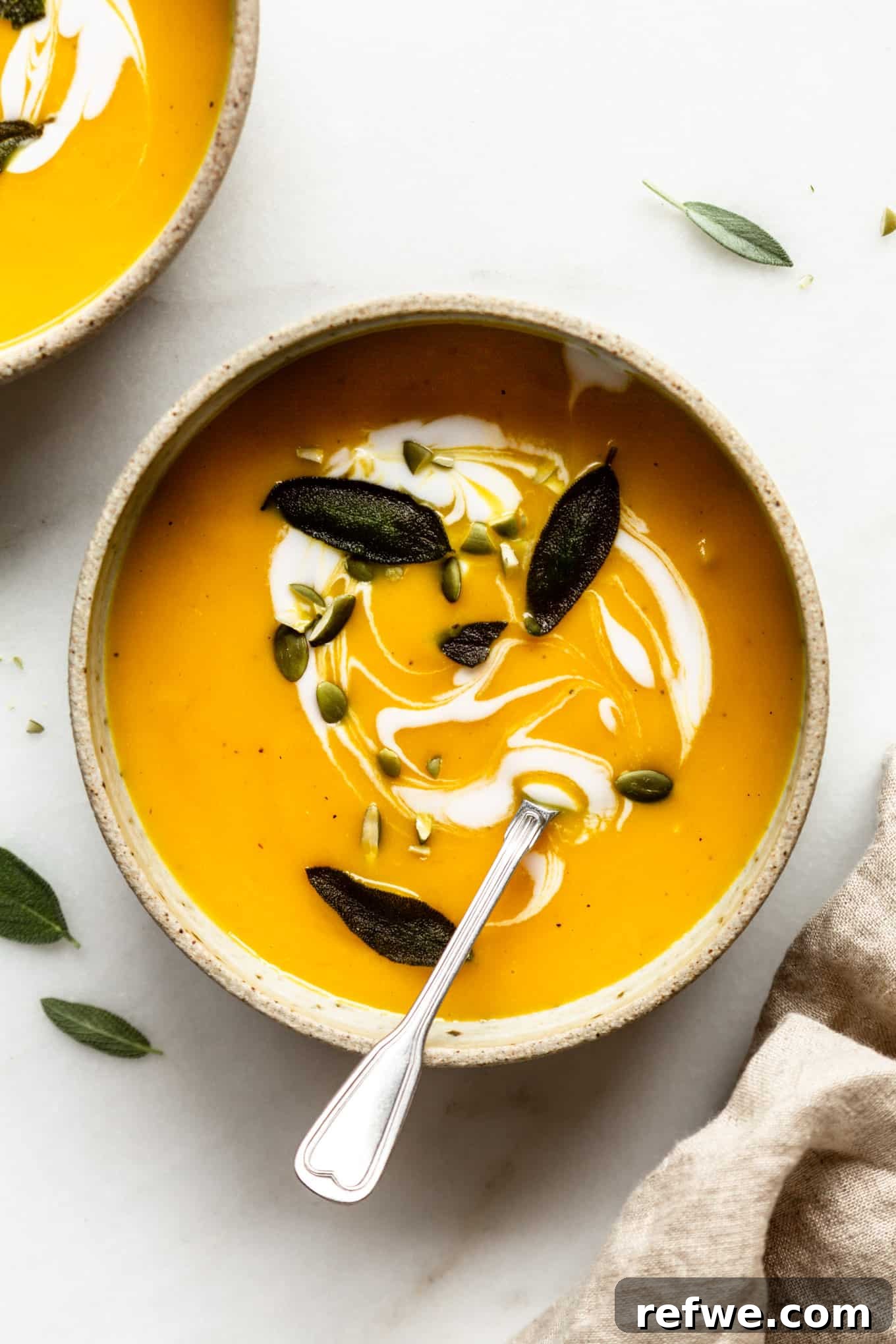 Roasted Autumn Acorn Bliss 2 A bowl of creamy roasted acorn squash soup, garnished with crispy fried sage leaves and crunchy pumpkin seeds, ready to be enjoyed on a chilly autumn day.