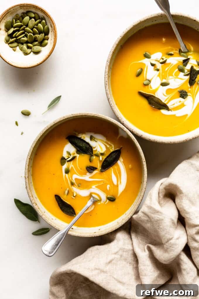 Roasted Autumn Acorn Bliss 11 Two inviting bowls of roasted acorn squash soup, beautifully garnished, placed on a table with a rustic napkin and a small bowl of pumpkin seeds on the side, inviting a cozy meal.