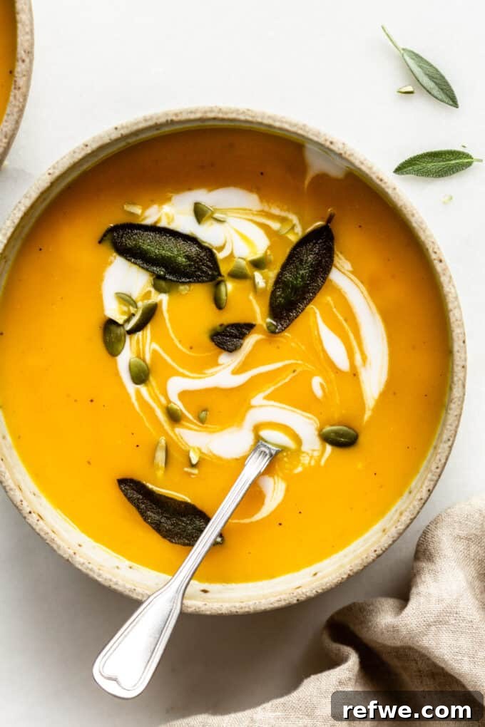 Roasted Autumn Acorn Bliss 12 A beautifully presented bowl of roasted acorn squash soup, topped generously with fresh sage, crunchy pumpkin seeds, and a swirl of coconut milk, set on a rustic background.