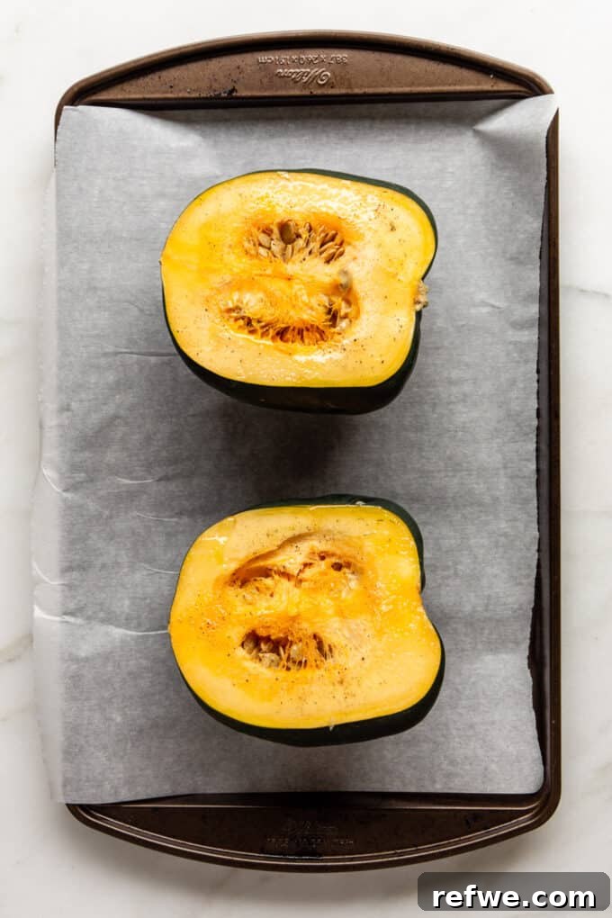 Roasted Autumn Acorn Bliss 4 An acorn squash expertly sliced in half, resting on a baking tray, ready for roasting.