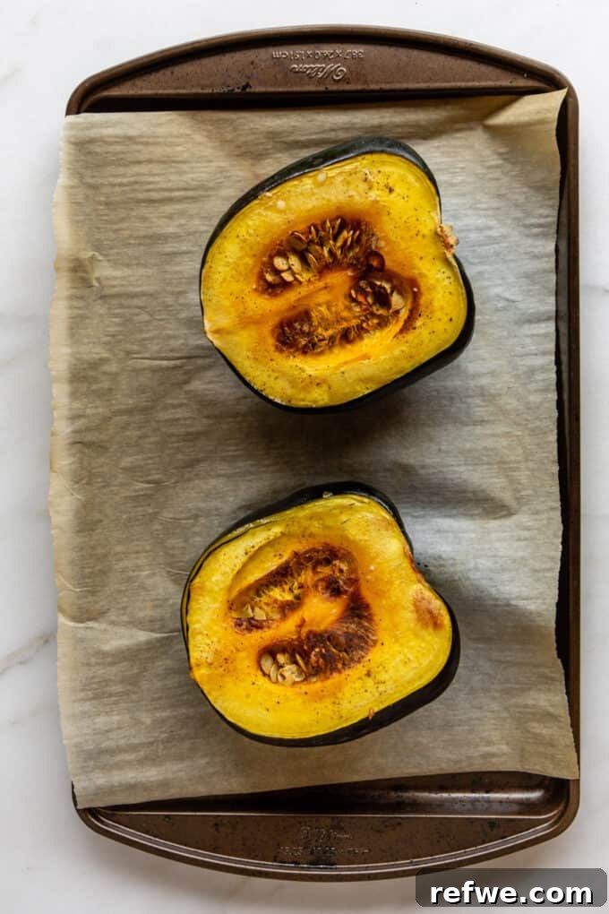 Roasted Autumn Acorn Bliss 5 A roasted acorn squash, perfectly tender and golden, cut in half and displayed on a baking tray after being removed from the oven.