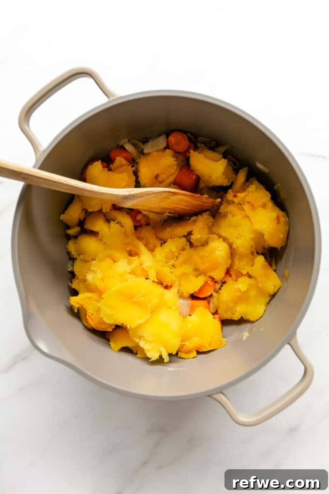 Roasted Autumn Acorn Bliss 7 The same large pot, now containing sautéed onions, garlic, and carrots, with the tender roasted acorn squash flesh added in, ready for the next step of soup preparation.