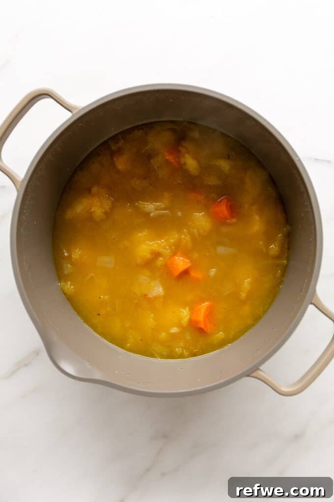 Roasted Autumn Acorn Bliss 9 A large pot of acorn squash soup gently simmering on a stovetop, covered with a lid, allowing the flavors to meld and deepen.