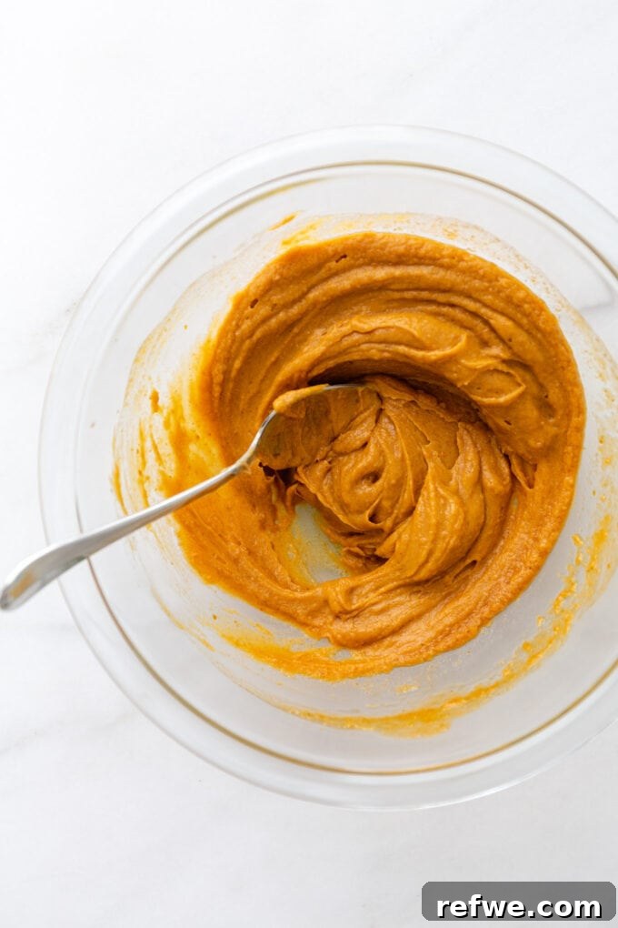 The thoroughly mixed pumpkin puree and almond butter mixture in a mixing bowl, ready for dry ingredients.