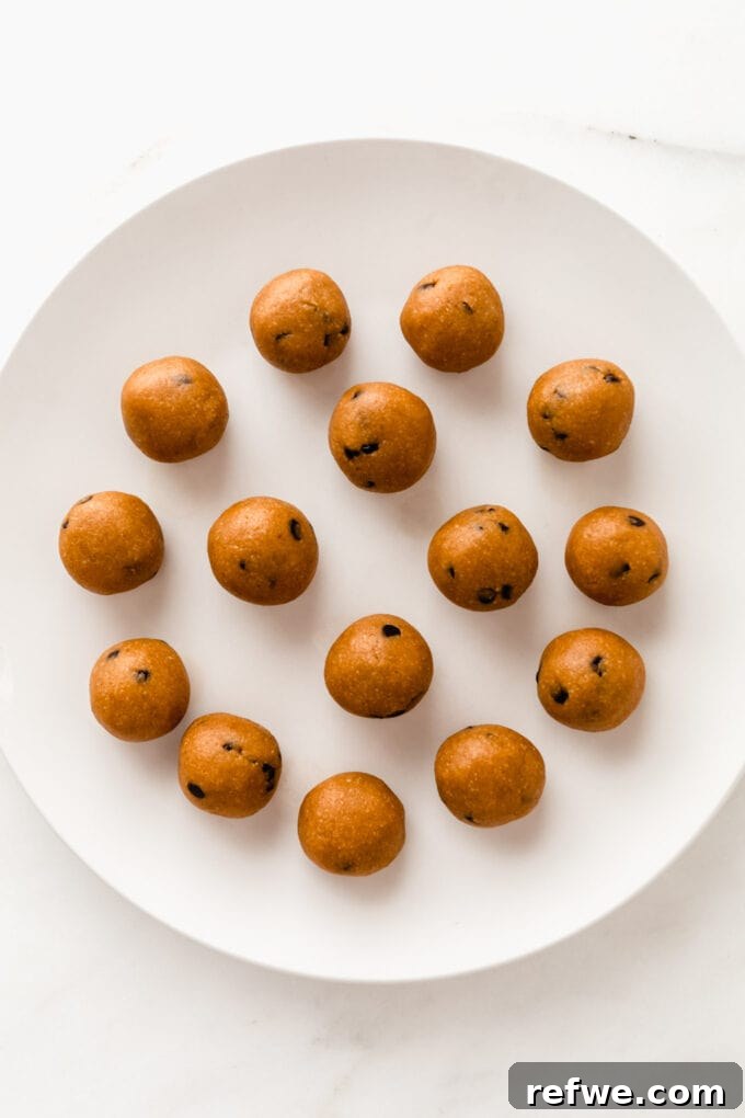 Perfectly rolled pumpkin protein balls arranged neatly on a white plate, ready for chilling.