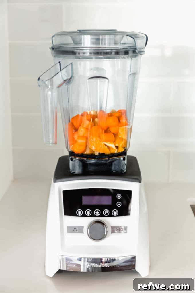 Zingy Ginger Carrot Orange Immunity Nectar 4 A blender filled with peeled and chopped oranges, carrots, and ginger, ready to be blended into a healthy juice.