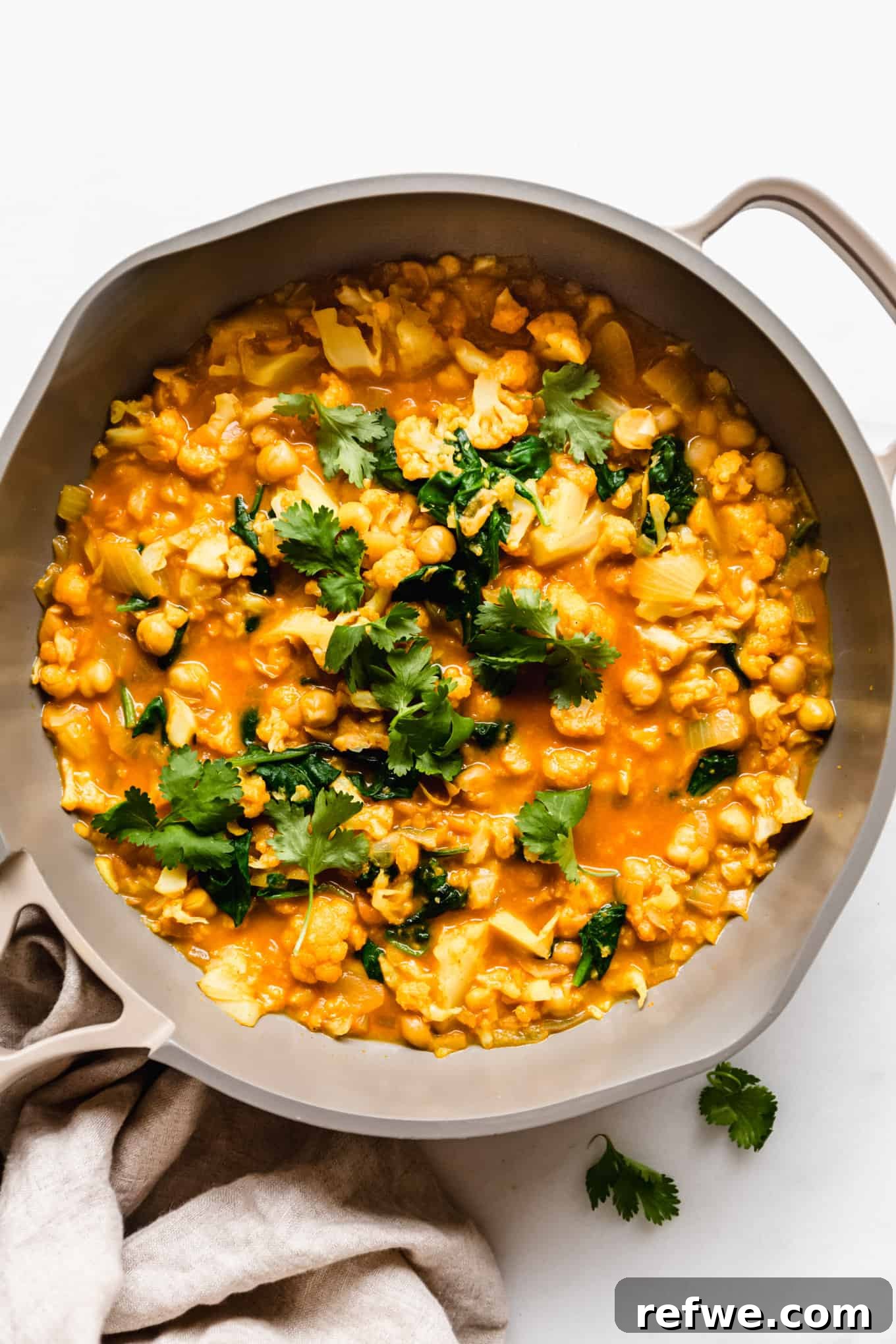 Golden Cauliflower Chickpea Curry 8 cauliflower curry topped with cilantro in a pan
