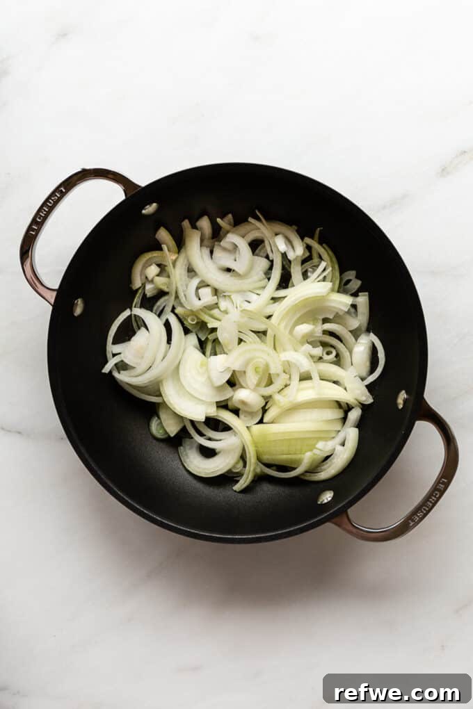 Creamy French Onion Pasta Skillet 4 Thinly sliced onions starting to soften and cook in a pot with oil and butter.