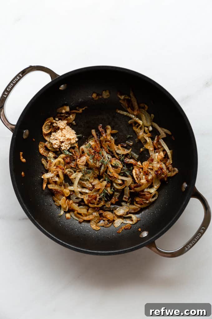 Creamy French Onion Pasta Skillet 6 Minced garlic and fresh thyme being added to the caramelized onions in the pot.