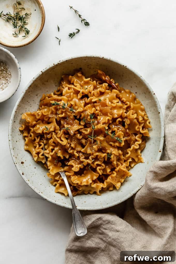 Creamy French Onion Pasta Skillet 10 A large serving of One-Pot French Onion Pasta garnished with fresh herbs in a rustic bowl.