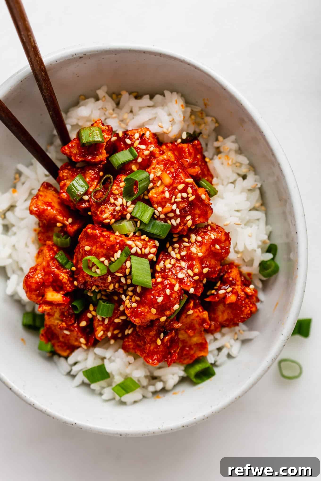 Gochujang Glazed Tofu 2 Crispy Gochujang Tofu in a bowl served over rice, garnished with fresh scallions.