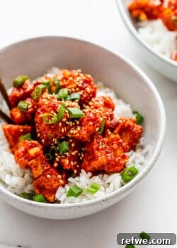 A bowl of glossy Gochujang Tofu topped with fresh scallions, ready to be served.