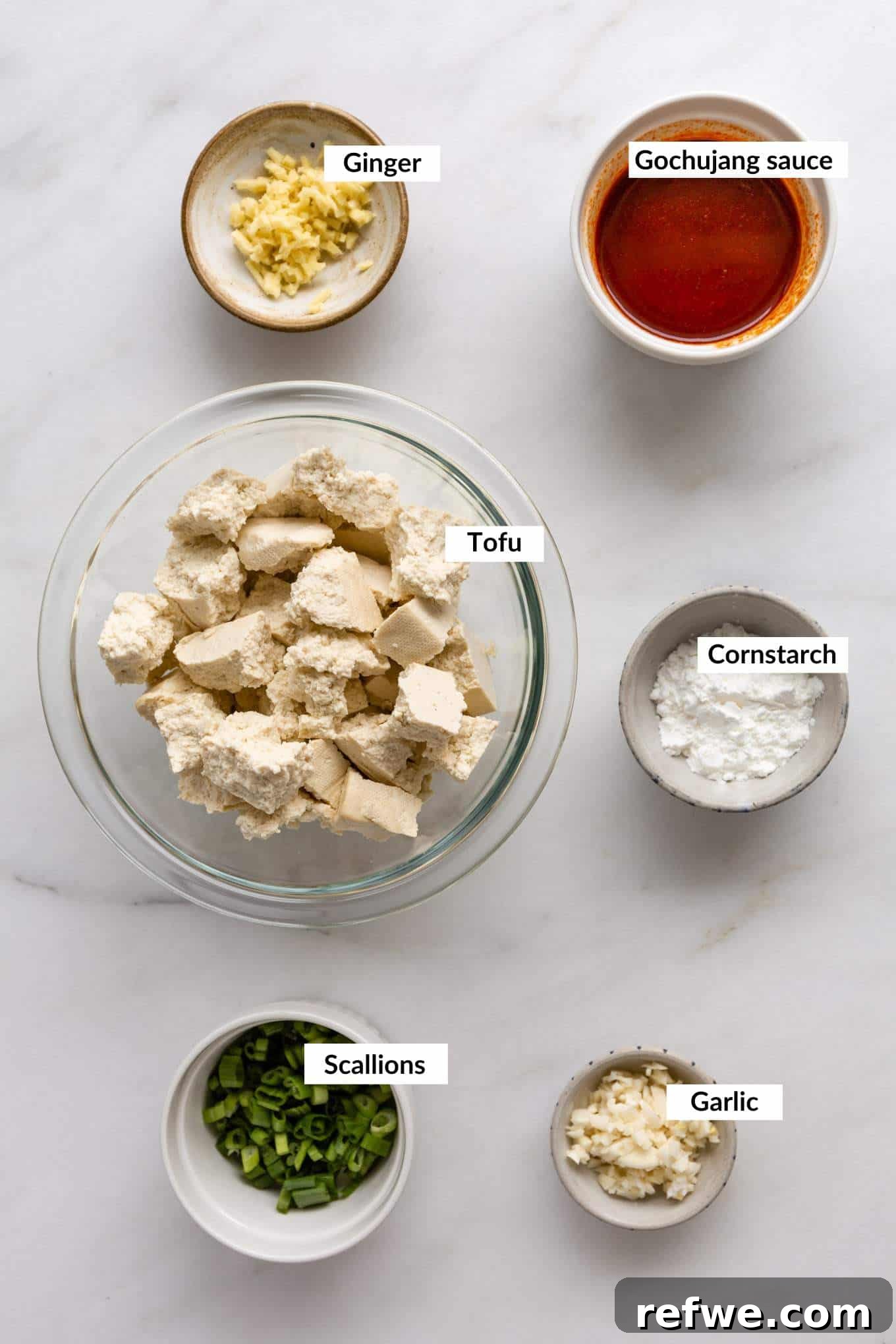 Gochujang Glazed Tofu 3 A vibrant selection of ingredients for Gochujang Tofu, including a block of tofu, a tub of Gochujang, and fresh aromatics.