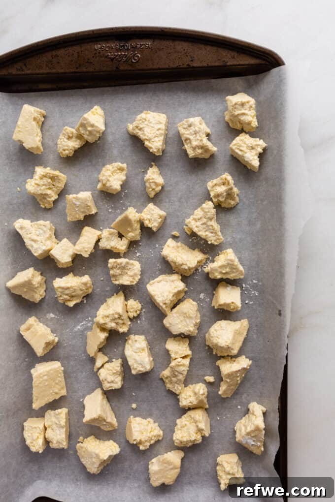 Gochujang Glazed Tofu 4 Tofu ripped into uneven nuggets on a parchment-lined baking sheet, ready for baking.
