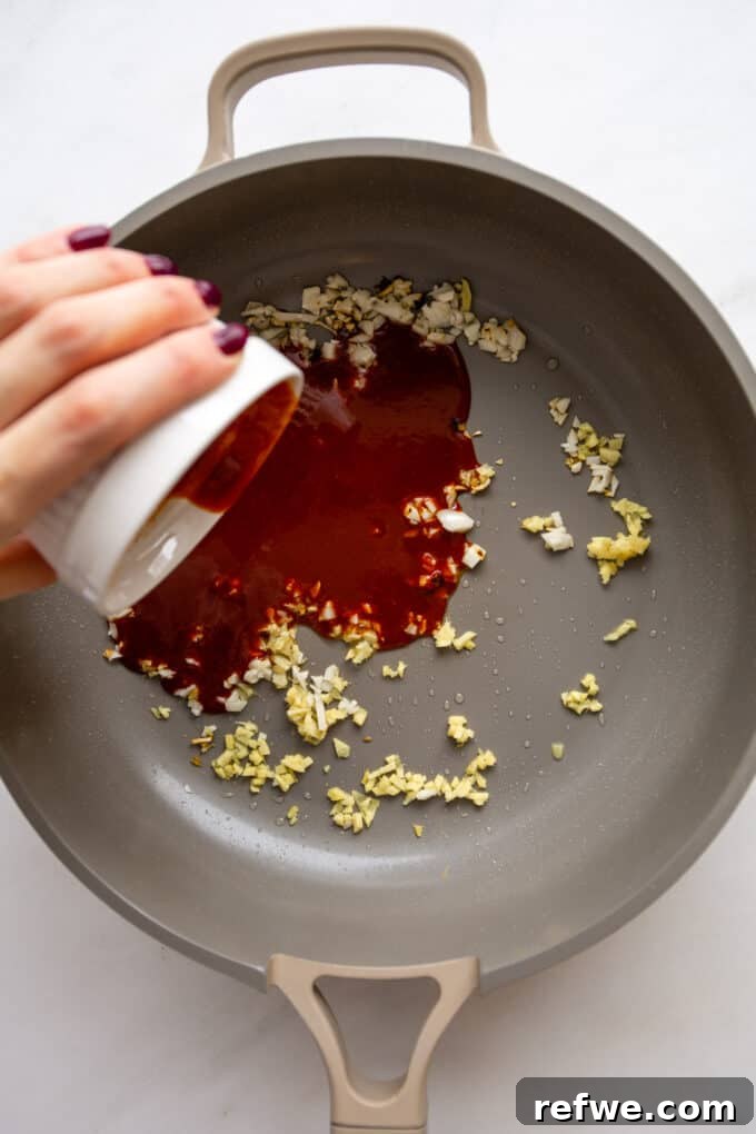 Gochujang Glazed Tofu 7 Thick Gochujang sauce being poured into a pan with sautéed aromatics.