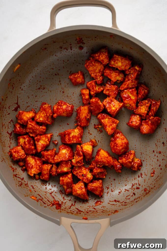 Gochujang Glazed Tofu 8 Crispy Gochujang Tofu pieces being tossed and coated evenly in a pan with the thick Gochujang sauce.