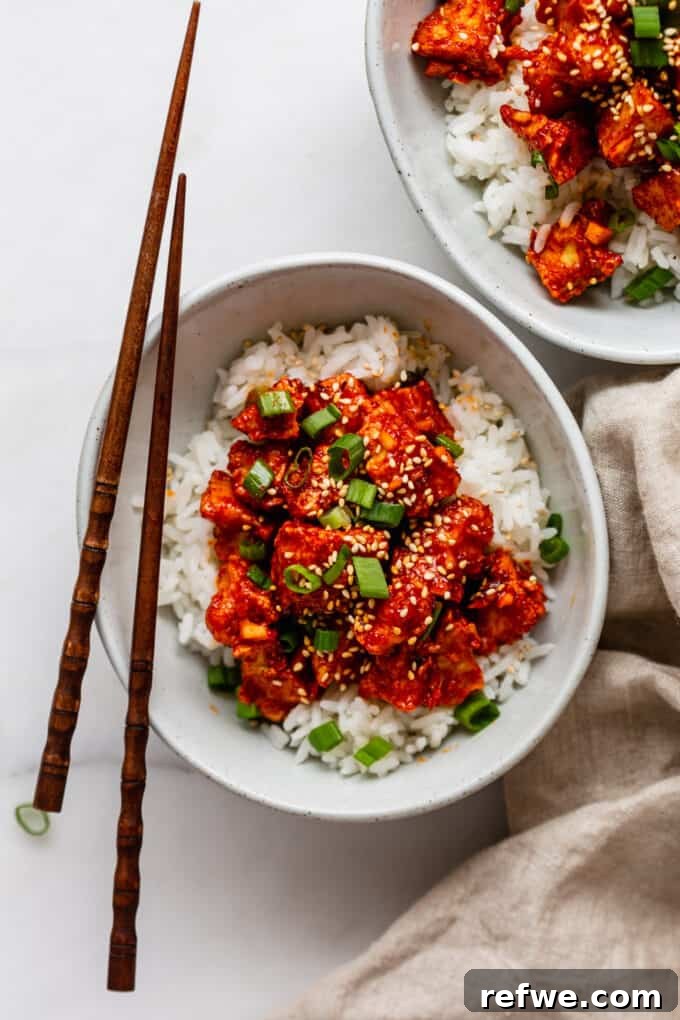 Gochujang Glazed Tofu 9 Two bowls of finished Gochujang Tofu with rice, garnished with scallions and sesame seeds, alongside chopsticks.
