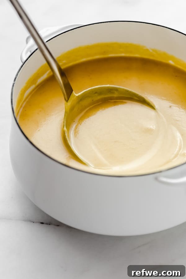 Velvety Curried Cauliflower Bliss 8 An immersion blender being used to blend the cauliflower soup directly in the white pot until smooth and creamy.