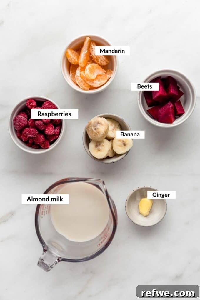 A collection of fresh ingredients laid out for making a beet smoothie, including beets, raspberries, bananas, and ginger.