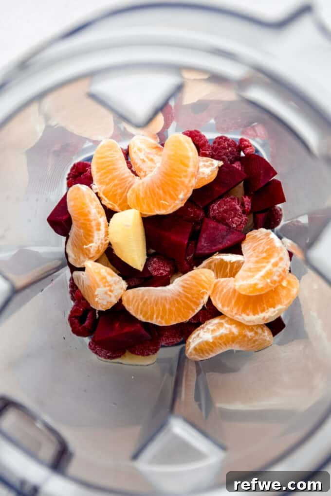 Beets, raspberries, and mandarin orange pieces ready in a blender before blending.