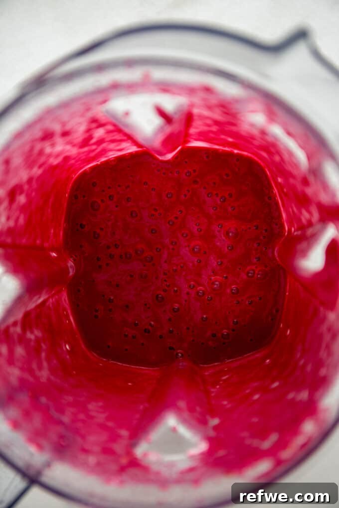 A vibrant beetroot smoothie being blended to a smooth consistency in a blender.