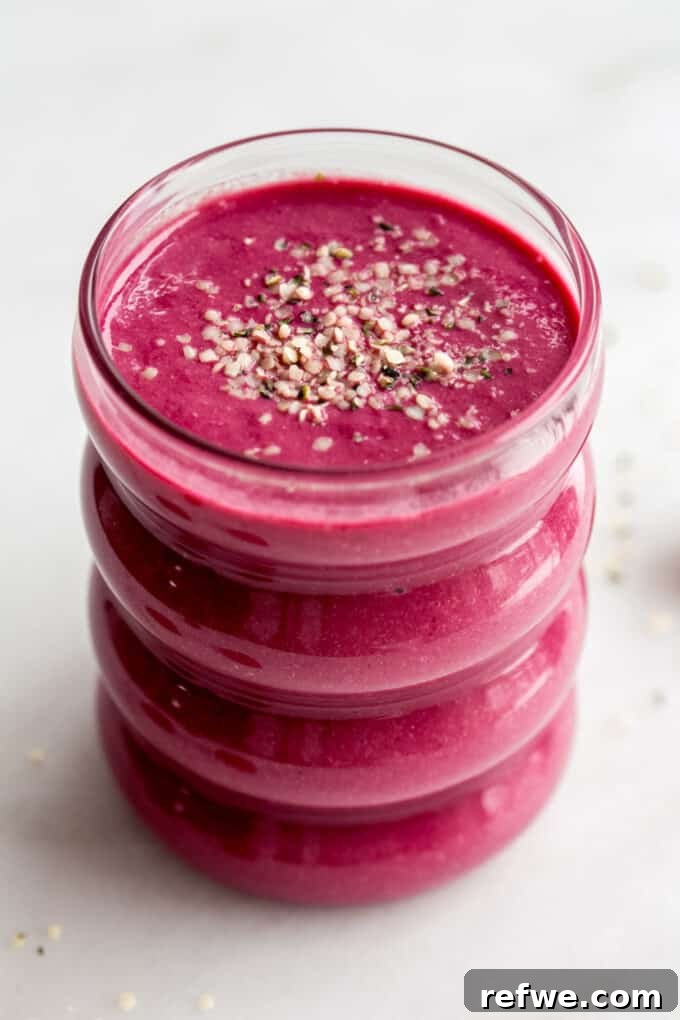 A beautifully presented beet smoothie in a glass, topped with a delicate sprinkle of hemp seeds, showcasing its vibrant color.