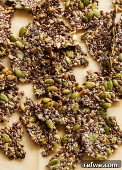 A selection of perfectly baked 5-seed crackers resting on parchment paper, ready to be enjoyed as a healthy and crunchy snack.