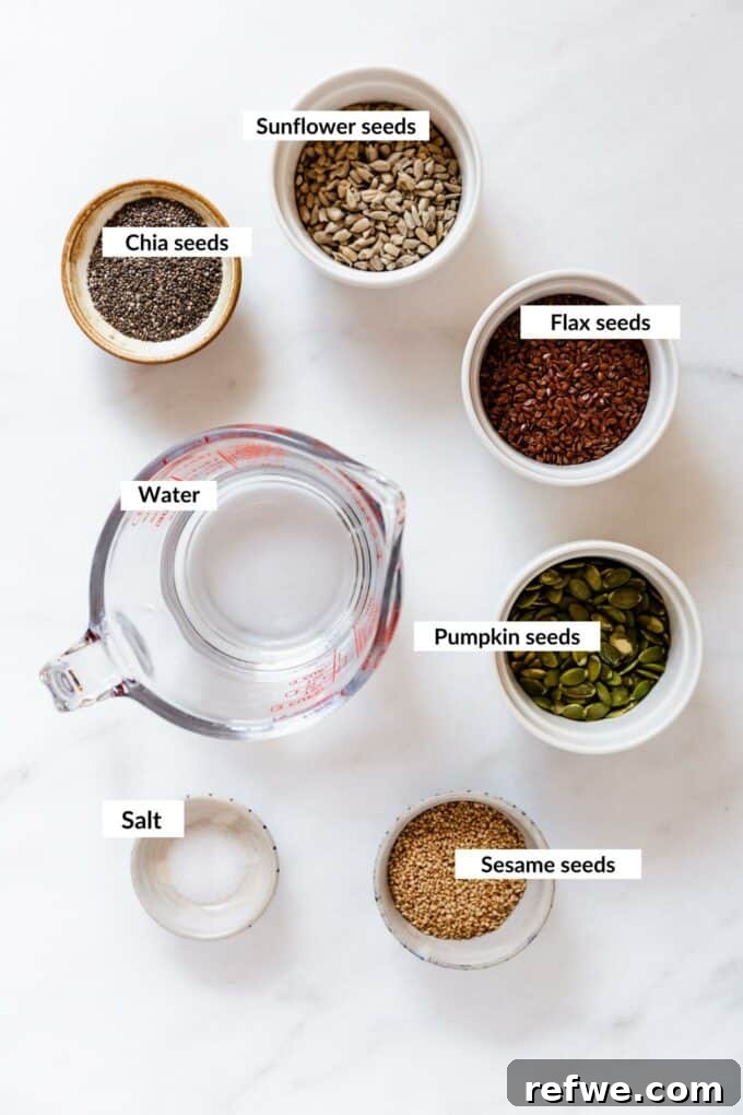 Effortless Flaxseed Crisps 3 A vibrant selection of the five key ingredients for flax crackers, including golden flax seeds, tiny chia seeds, flat pumpkin seeds, oval sunflower seeds, and small sesame seeds, neatly arranged on a white background.