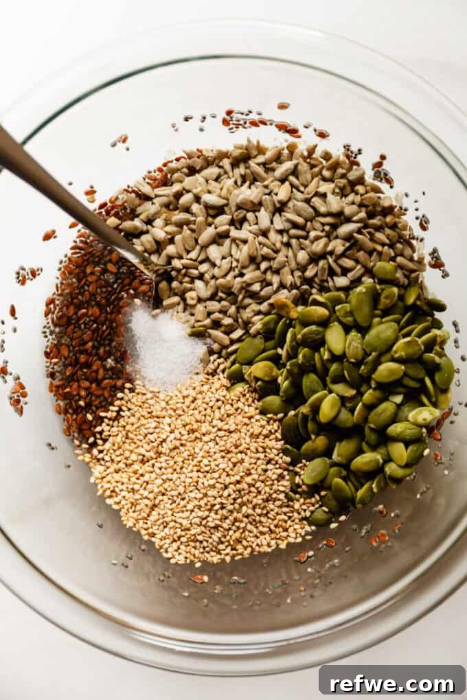 Effortless Flaxseed Crisps 6 Various seeds, including sunflower, pumpkin, and sesame, are added to a clear mixing bowl containing the flax and chia seed gel, ready to be combined.