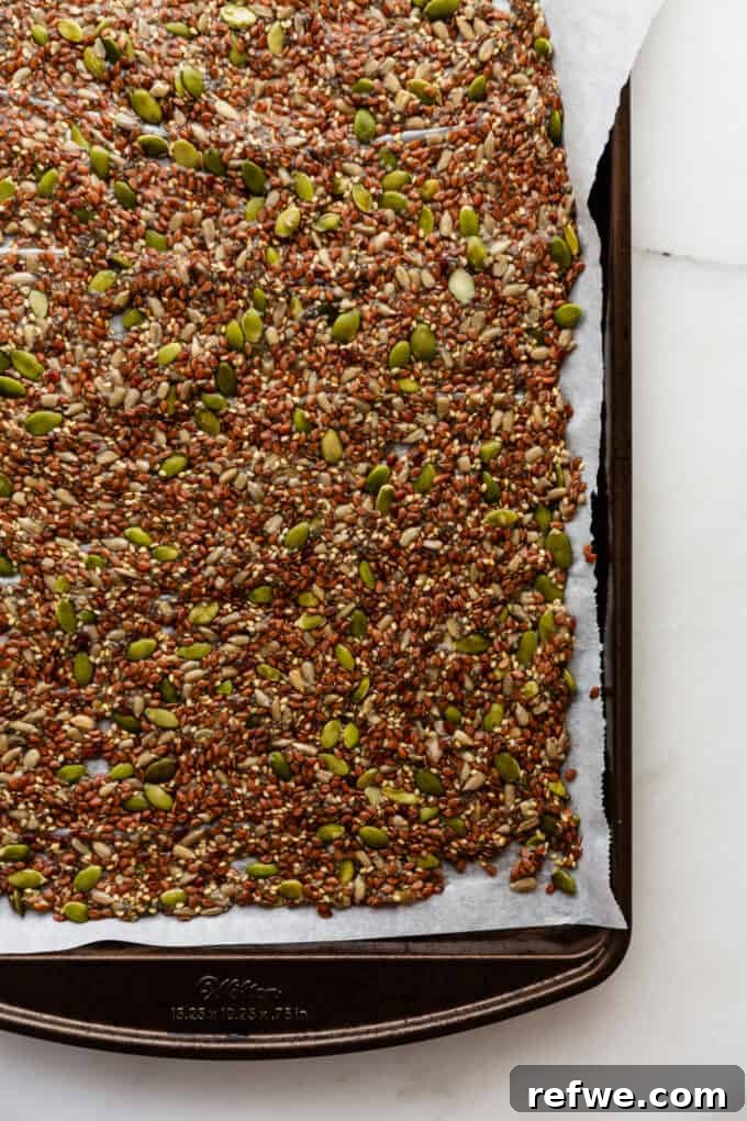 Effortless Flaxseed Crisps 8 The unbaked flax cracker mixture spread thinly and evenly on a baking sheet lined with parchment paper, ready for the oven.
