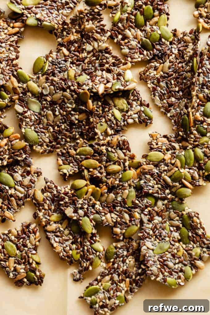 Effortless Flaxseed Crisps 10 A beautifully composed shot of five different seed crackers resting elegantly on parchment paper, highlighting their perfect golden hue and diverse textures, ready for enjoyment.