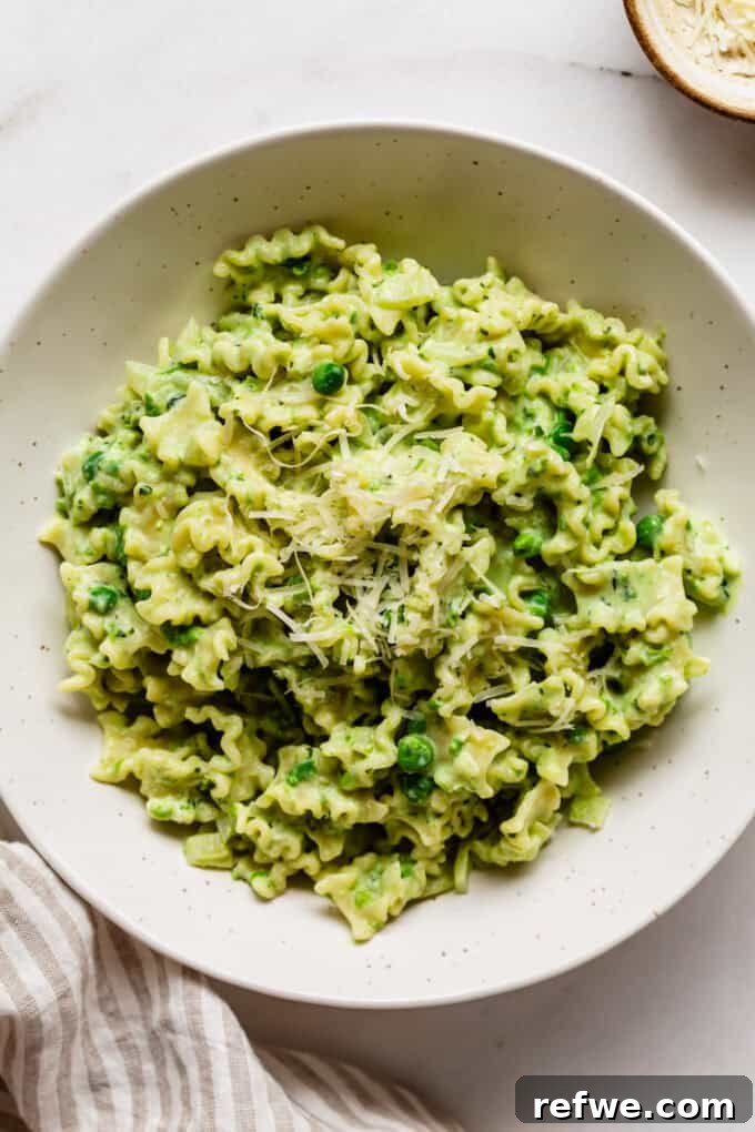 Spring Pea Ricotta Pasta 11 A close-up shot of creamy ricotta and pea pasta in a bowl, generously topped with grated Parmesan cheese and fresh basil.