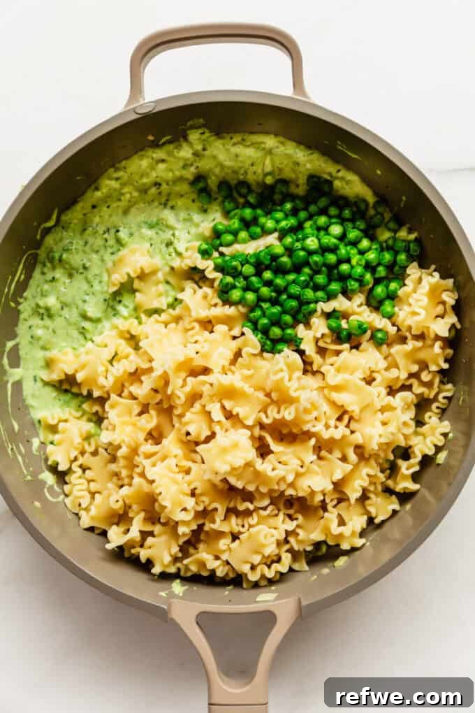 Spring Pea Ricotta Pasta 8 Cooked pasta, creamy ricotta sauce, and fresh peas being mixed together in a large pan.