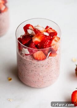 A jar of healthy Strawberry Overnight Oats, garnished with fresh strawberry pieces on top.