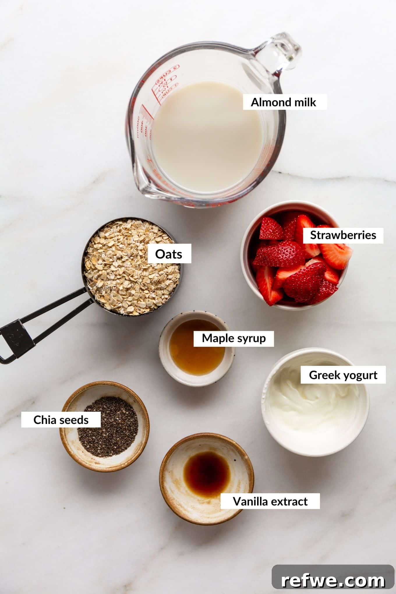 Dreamy Strawberry Overnight Oats 3 A flat lay image displaying the key ingredients for making strawberry overnight oats, including oats, chia seeds, Greek yogurt, and fresh strawberries.