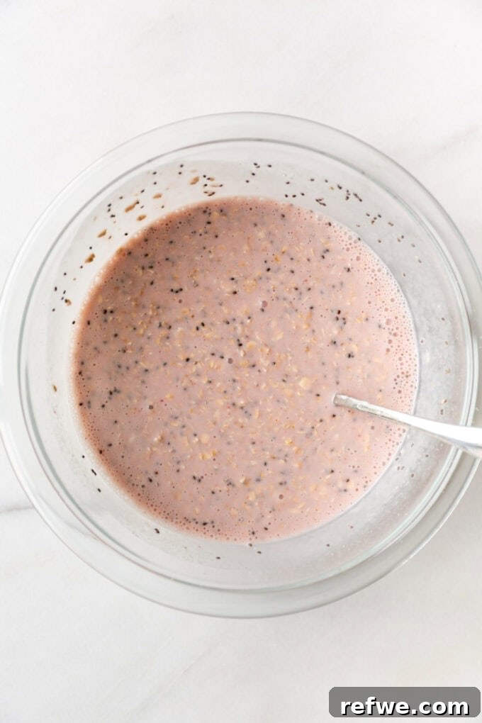 Dreamy Strawberry Overnight Oats 7 The blended strawberry milk is poured into a clear mixing bowl with the oats, chia seeds, and Greek yogurt, ready to be combined.