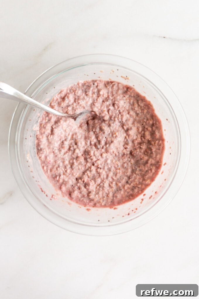 Dreamy Strawberry Overnight Oats 8 The strawberry overnight oats mixture rests in a clear mixing bowl, covered, and placed in the fridge to set overnight.